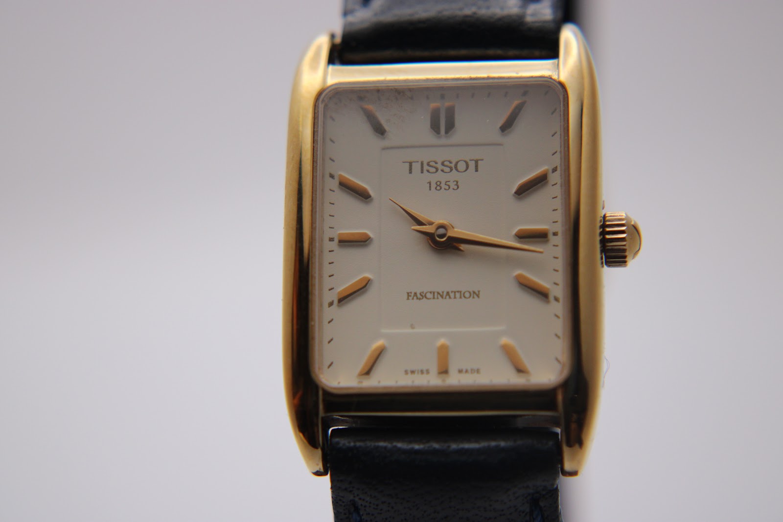 Close-up front view of the Tissot T815 Fascination watch, showcasing its white dial with applied gold baton indices.
