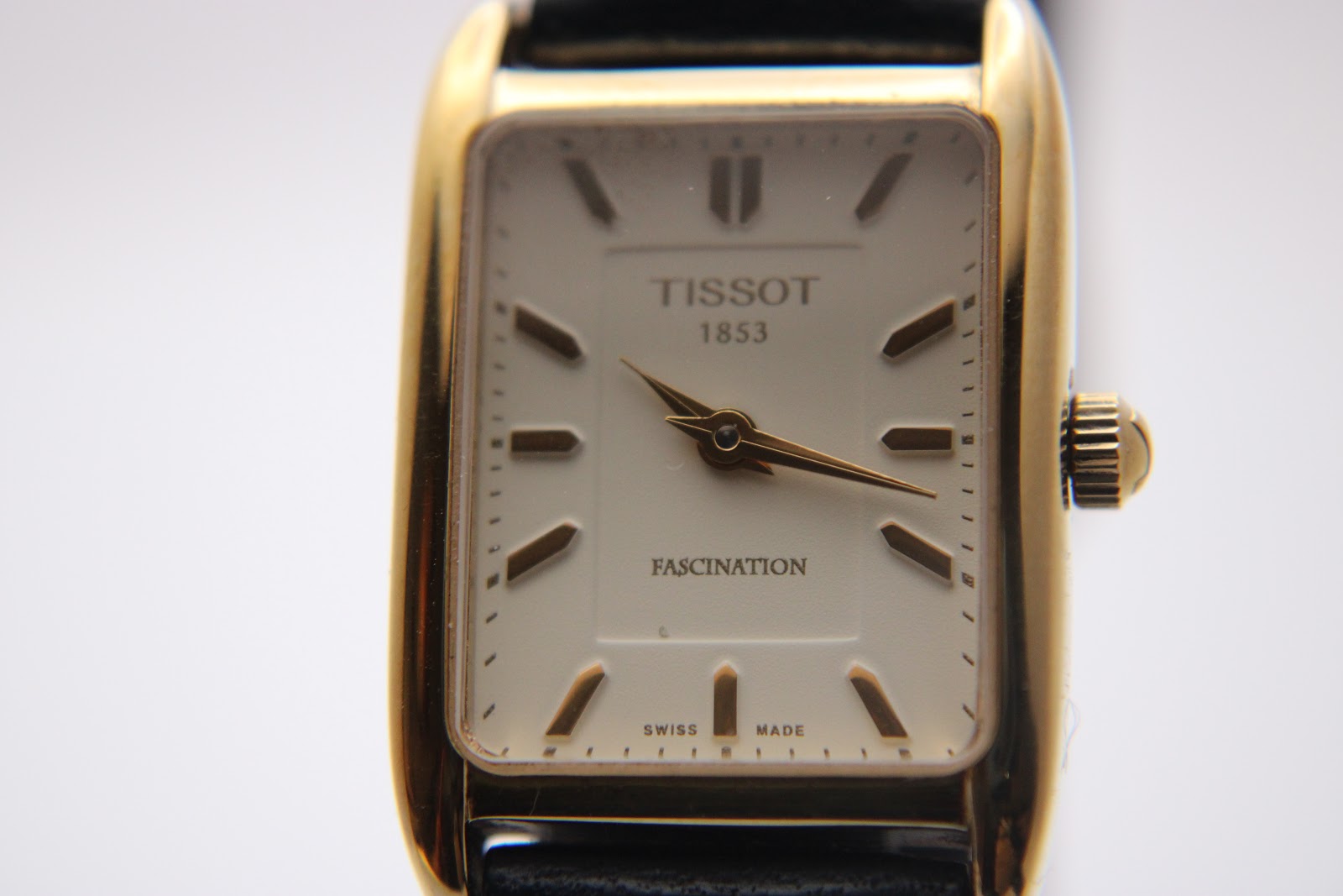 Front view of the Tissot T815 Fascination watch with its rectangular gold-tone case and white dial.