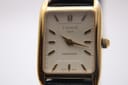 Front view of the Tissot T815 Fascination watch with its rectangular gold-tone case and white dial.