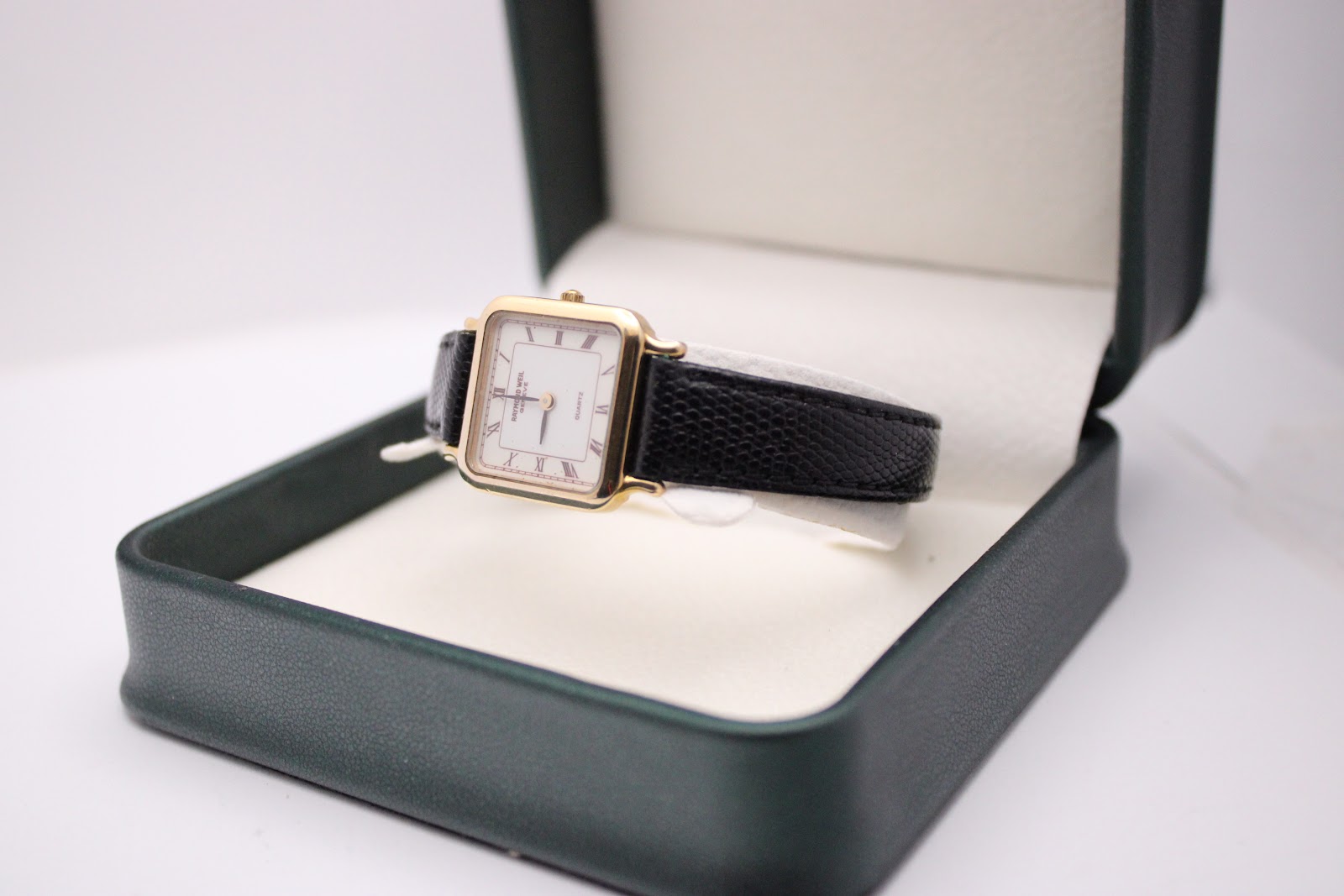 The Raymond Weil 5748 watch displayed on a stand inside an open dark green presentation box, highlighting the watch's design.