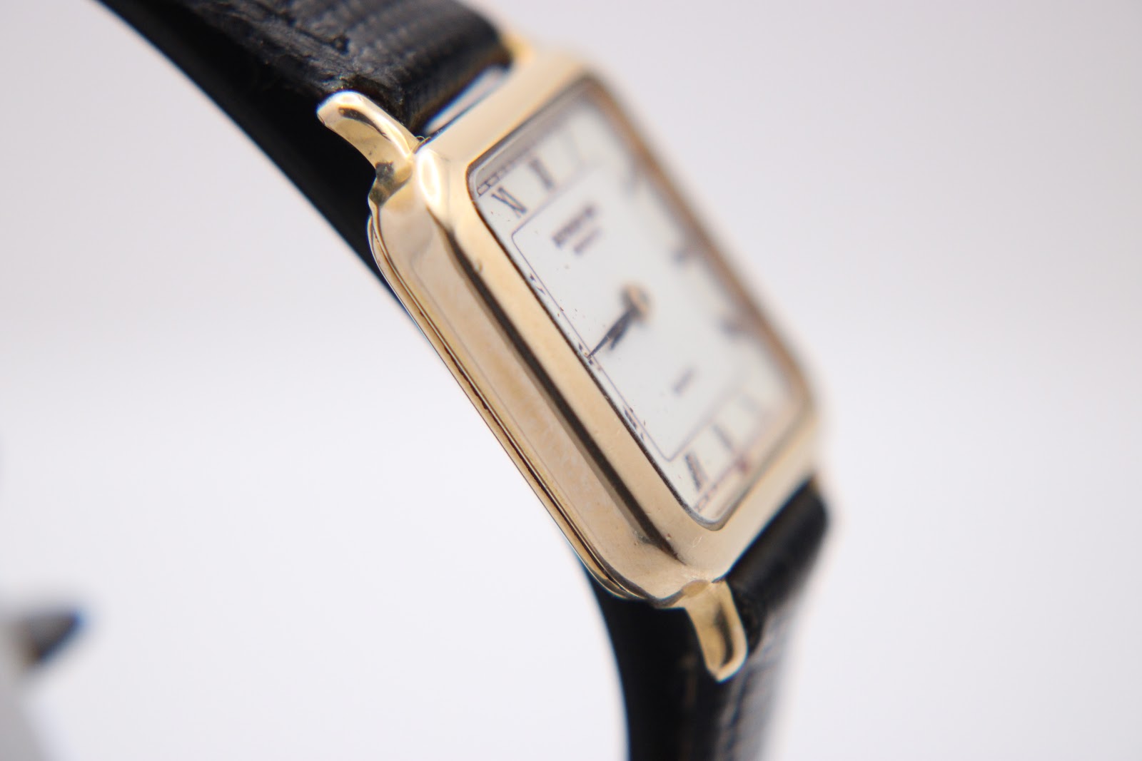 Another close-up side view of the Raymond Weil 5748 watch, showing the rectangular case profile and the textured black leather strap.