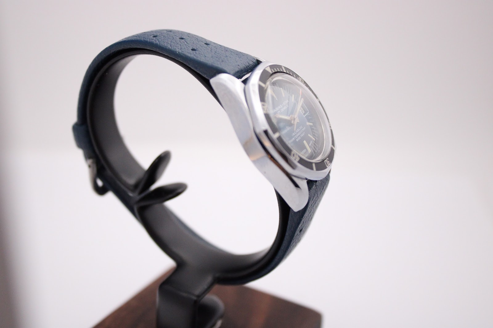 Another angled side view of the Marine Star watch on a stand, showing the case lugs and the textured dark blue rubber strap.