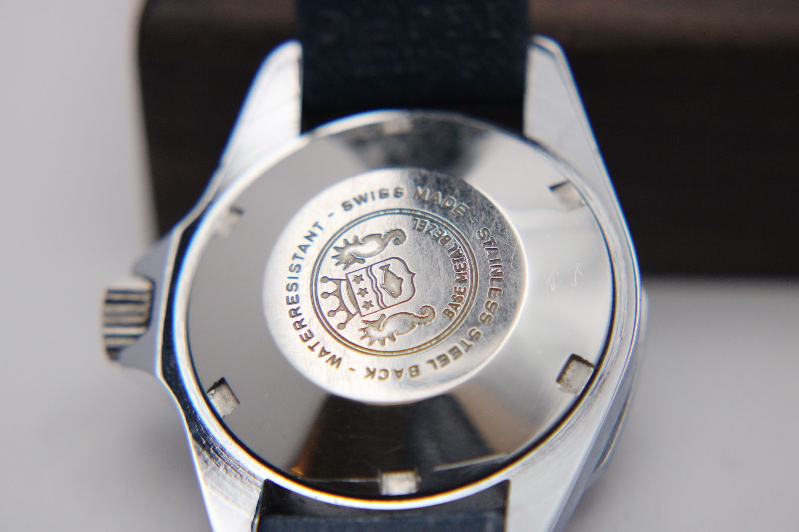 Detail shot of the stainless steel screw-down case back with "SWISS MADE", "WATERRESISTANT", and an engraved emblem.