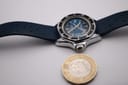 Top-down view of the Marine Star watch next to a UK one pound coin, illustrating its compact size.