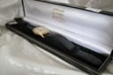 Overhead view of the gold-tone Services Marine watch with black leather strap resting inside an open Stephen Conway presentation box.