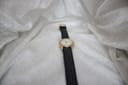 Full overhead shot of the Services Marine watch with its black leather strap laid flat on a textured white fabric background.