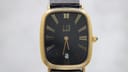 Front view of the Dunhill HQ 812572 quartz watch, showing the black dial, gold Roman numerals, and rectangular gold-toned case.