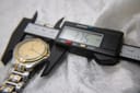 Close-up of digital caliper measuring Gucci 8040M case diameter at 37.5mm.