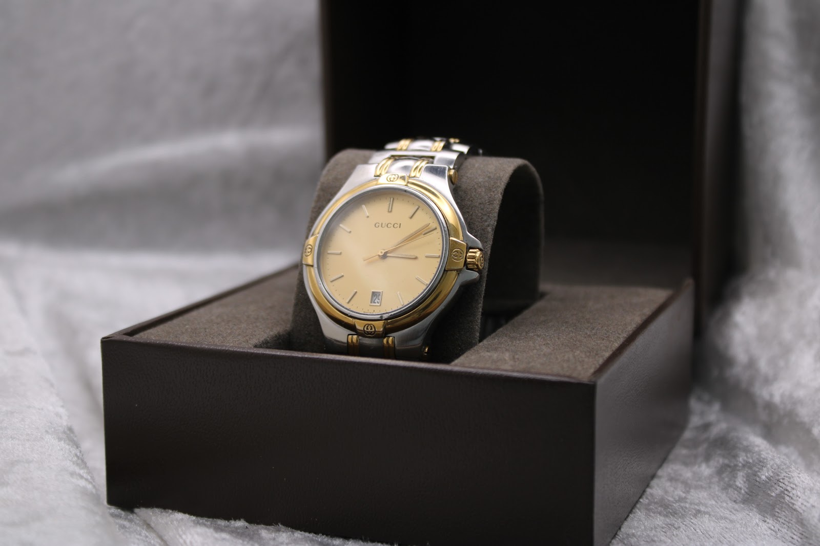 Angled view of Gucci 8040M two-tone watch presented in a brown box.