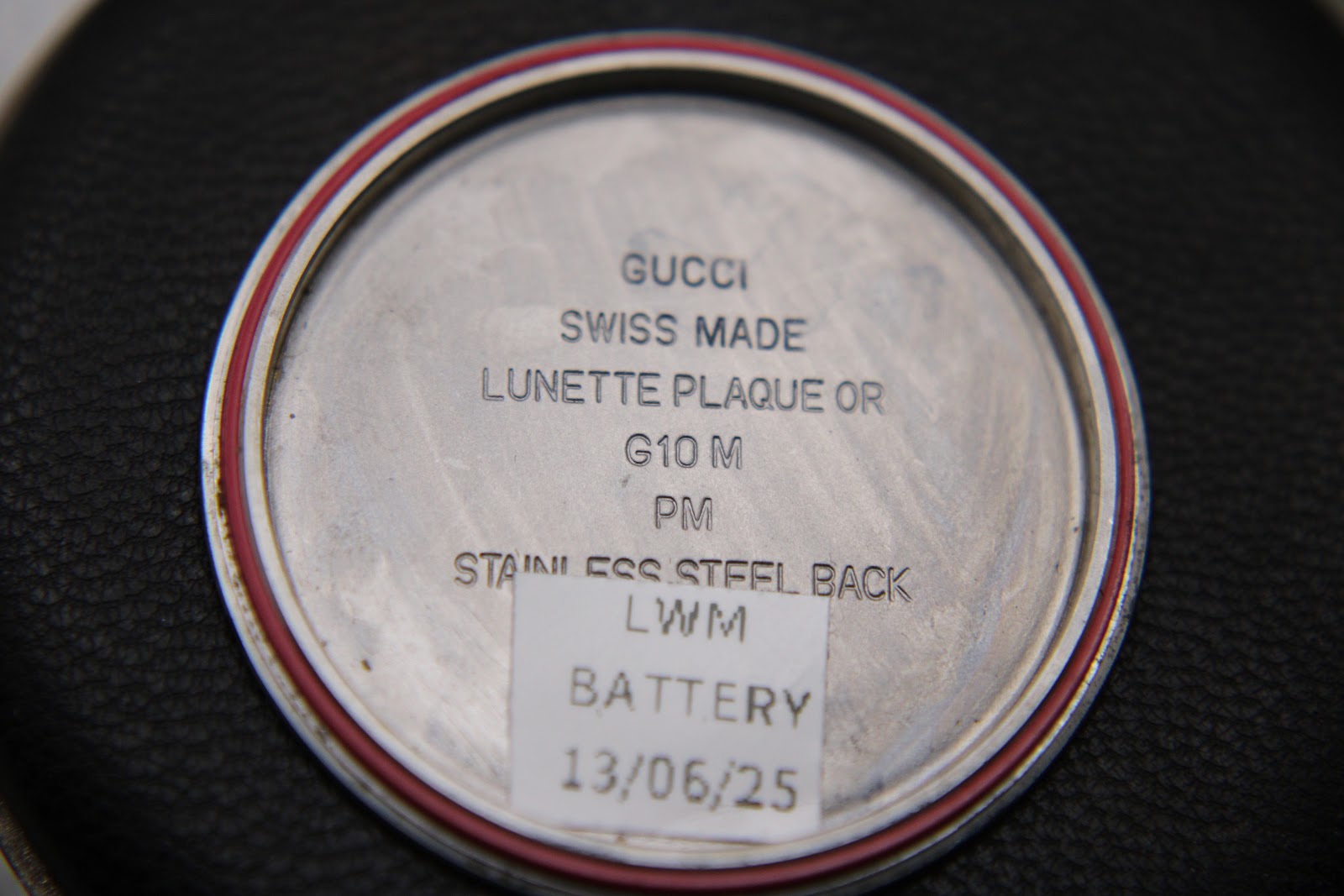 Close-up of the inside case back engraving 'Gucci Swiss Made' and battery replacement sticker.