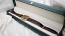 The Raymond Weil watch neatly displayed inside a dark green presentation box with white interior lining.