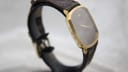 Side profile view of the slim Raymond Weil watch, highlighting its elegant rectangular gold-tone case.