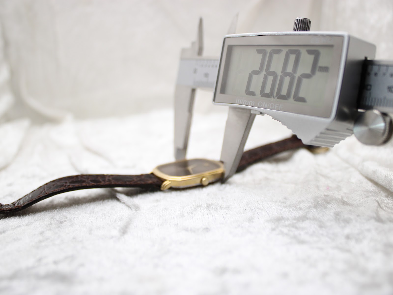 Digital caliper measuring the watch case width, displaying a precise reading of 26.82mm.
