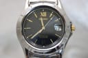 Close-up front view of the Seiko perpetual calendar black dial with gold Roman XII, baton indices, date magnifier, and luminous hands.