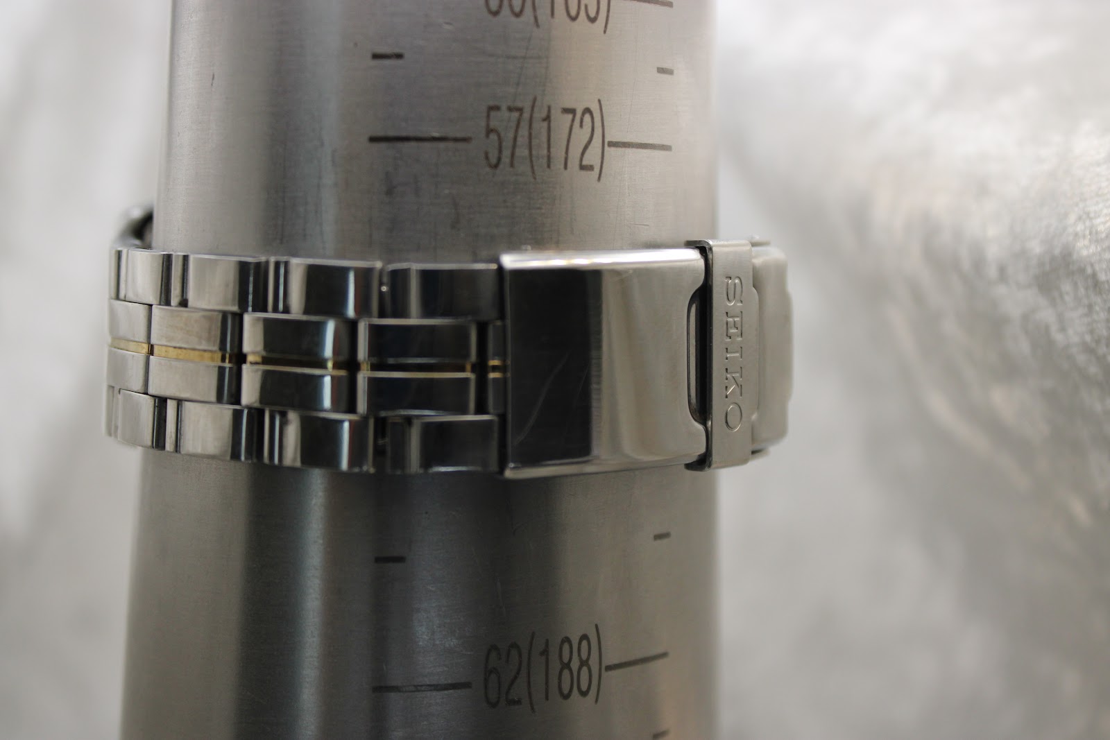 Close-up of the two-tone stainless steel bracelet and signed deployant clasp on a wrist sizing cone showing 172mm.