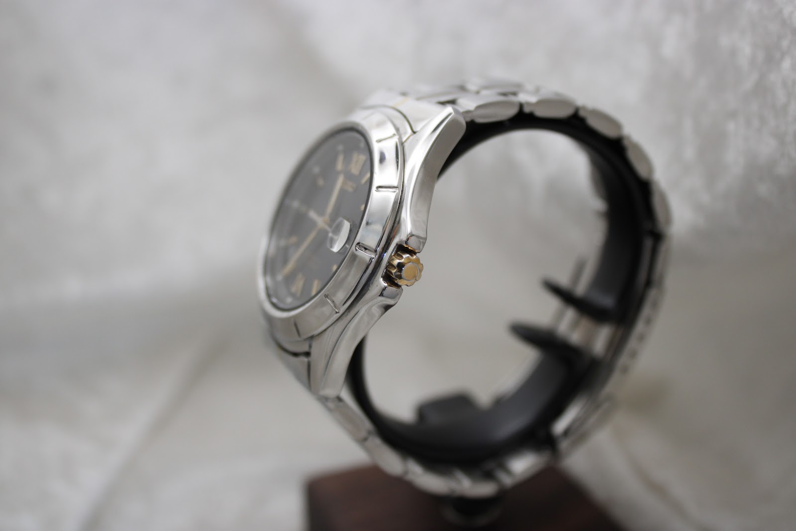 Side view of the Seiko watch on a display stand, highlighting the polished case and gold-tone crown.