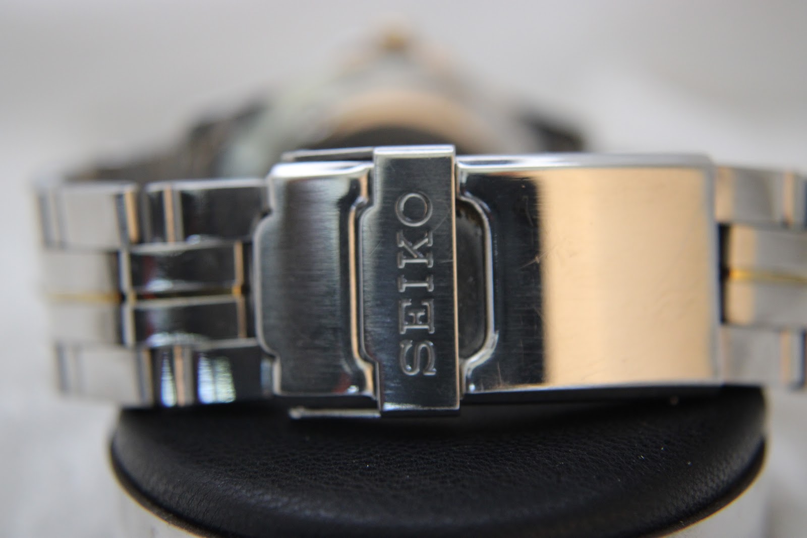 Extreme close-up of the Seiko signed deployant clasp on the two-tone stainless steel bracelet.
