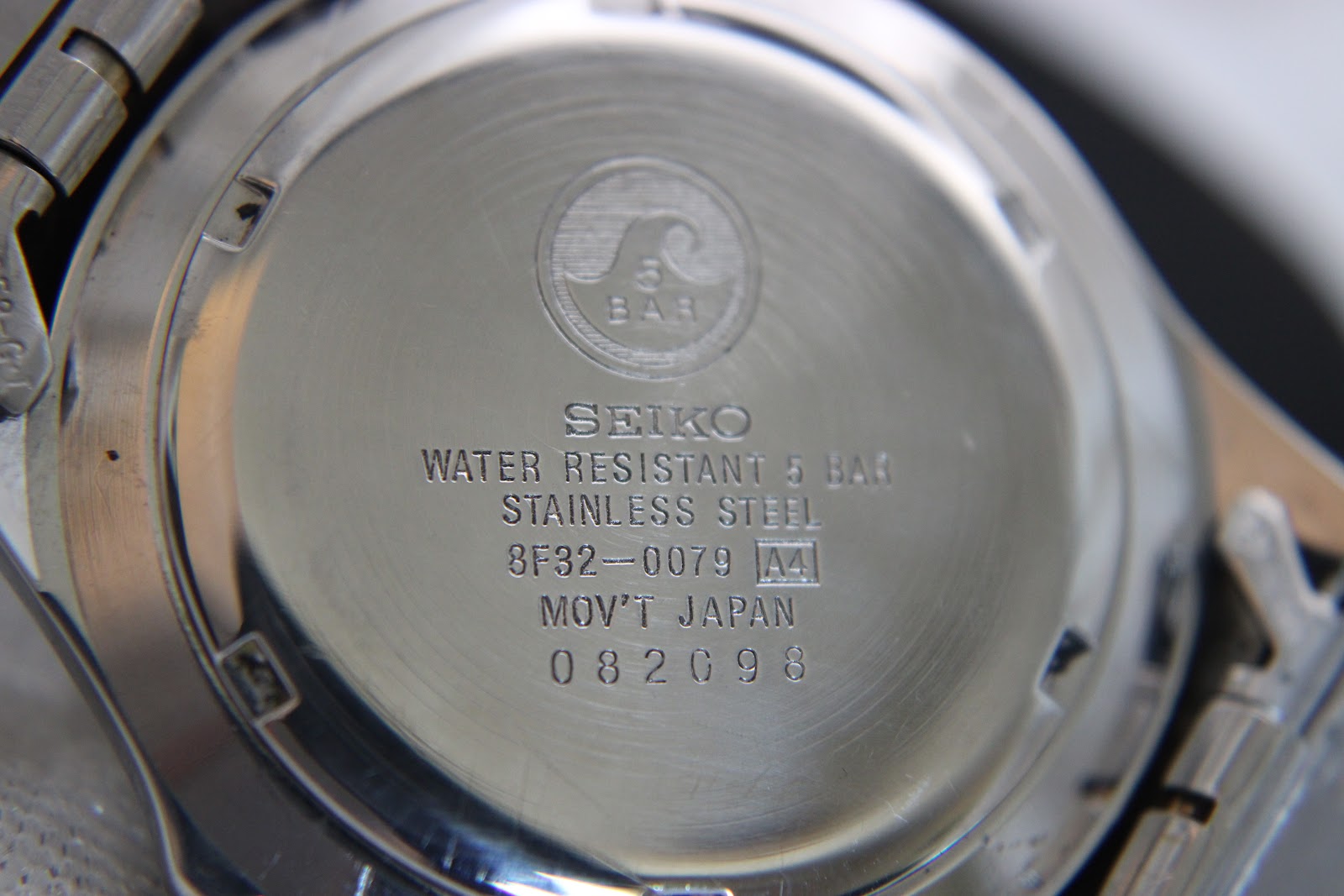 Close-up of the polished stainless steel case back, showing Seiko branding, water resistance, model number 8F32-0079, and serial 082098.