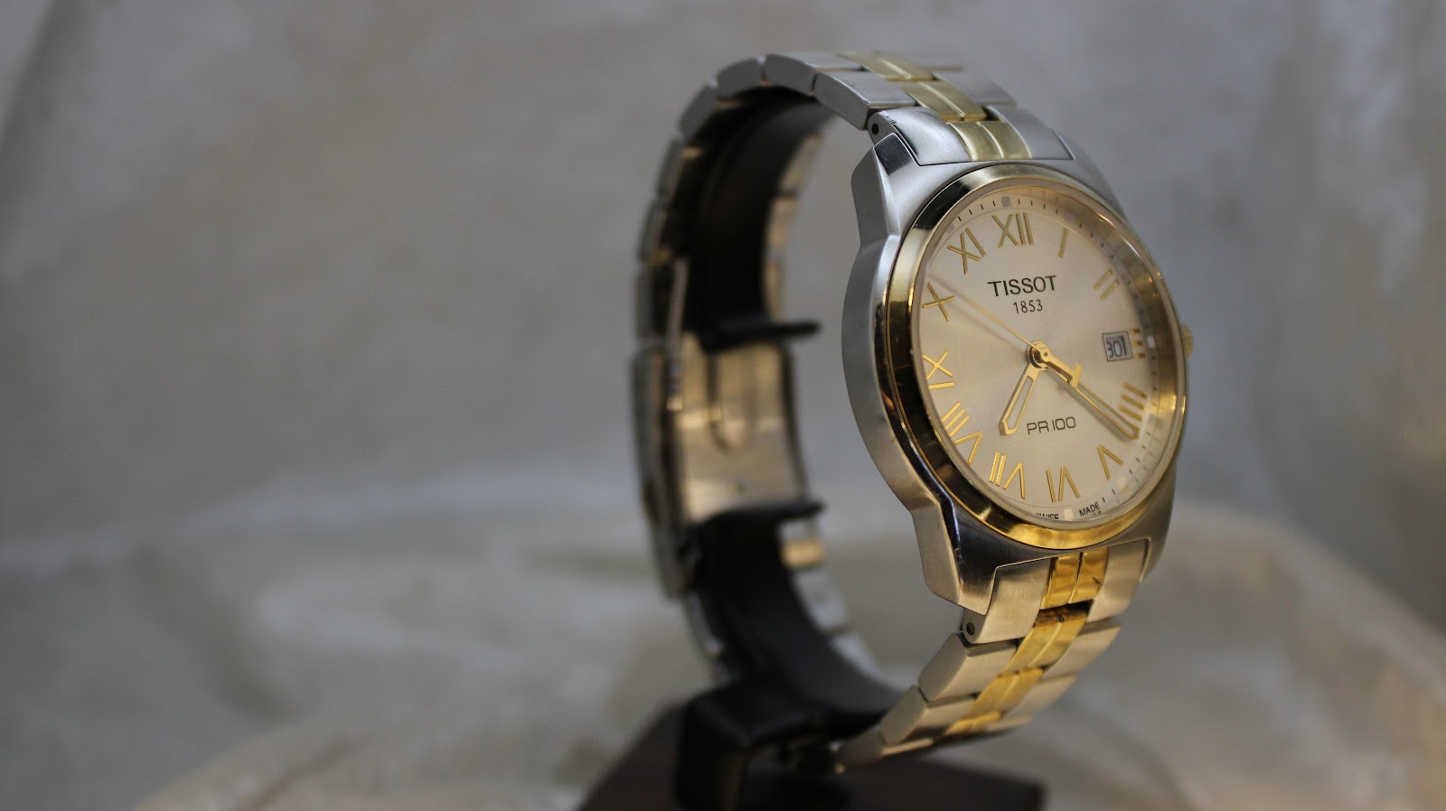 Side profile of the Tissot PR 100 showing its two-tone case and crown detail.