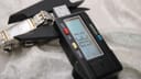Digital caliper measuring the watch case, displaying a width of 13.30 mm, with the watch resting on a white textured background.