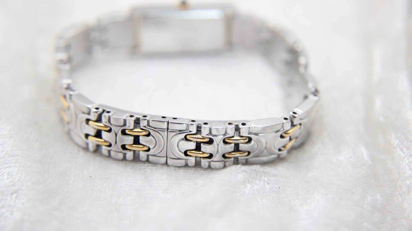 Close-up of the two-tone bracelet's curved underside, showing the alternating silver and gold-tone links and their polished finish.