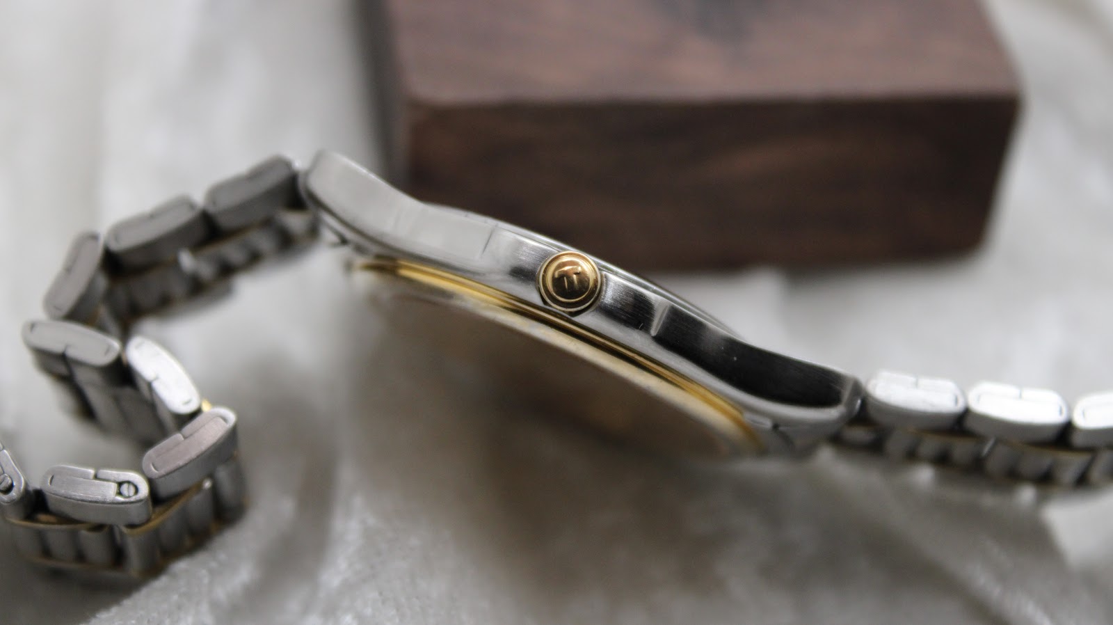 Side view of the Tissot PR 50 case, highlighting the brushed stainless steel finish and the gold-tone crown with the Tissot 'T' logo.