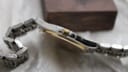 Side view of the Tissot PR 50 case, highlighting the brushed stainless steel finish and the gold-tone crown with the Tissot 'T' logo.