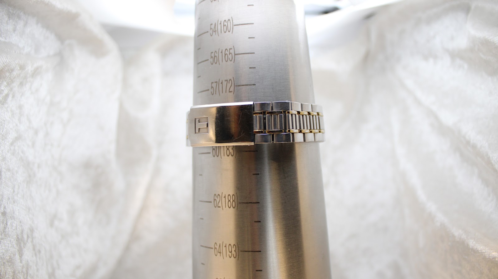 The Tissot PR 50's bi-metal bracelet clasped around a wrist sizing gauge, indicating a fit of approximately 180mm or 18cm.