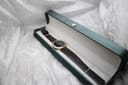 The Gucci 3000M watch resting in a generic dark green watch box with a white interior.
