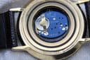 Close-up of the opened case back revealing the blue Swiss V8 quartz movement with six jewels and battery.