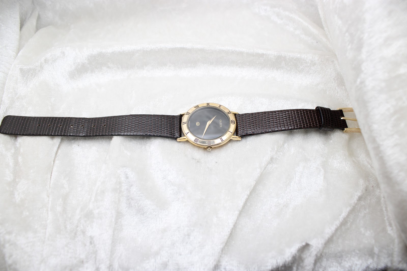 Full length top-down view of the Gucci 3000M watch, displaying the black dial and brown leather strap on a white background.