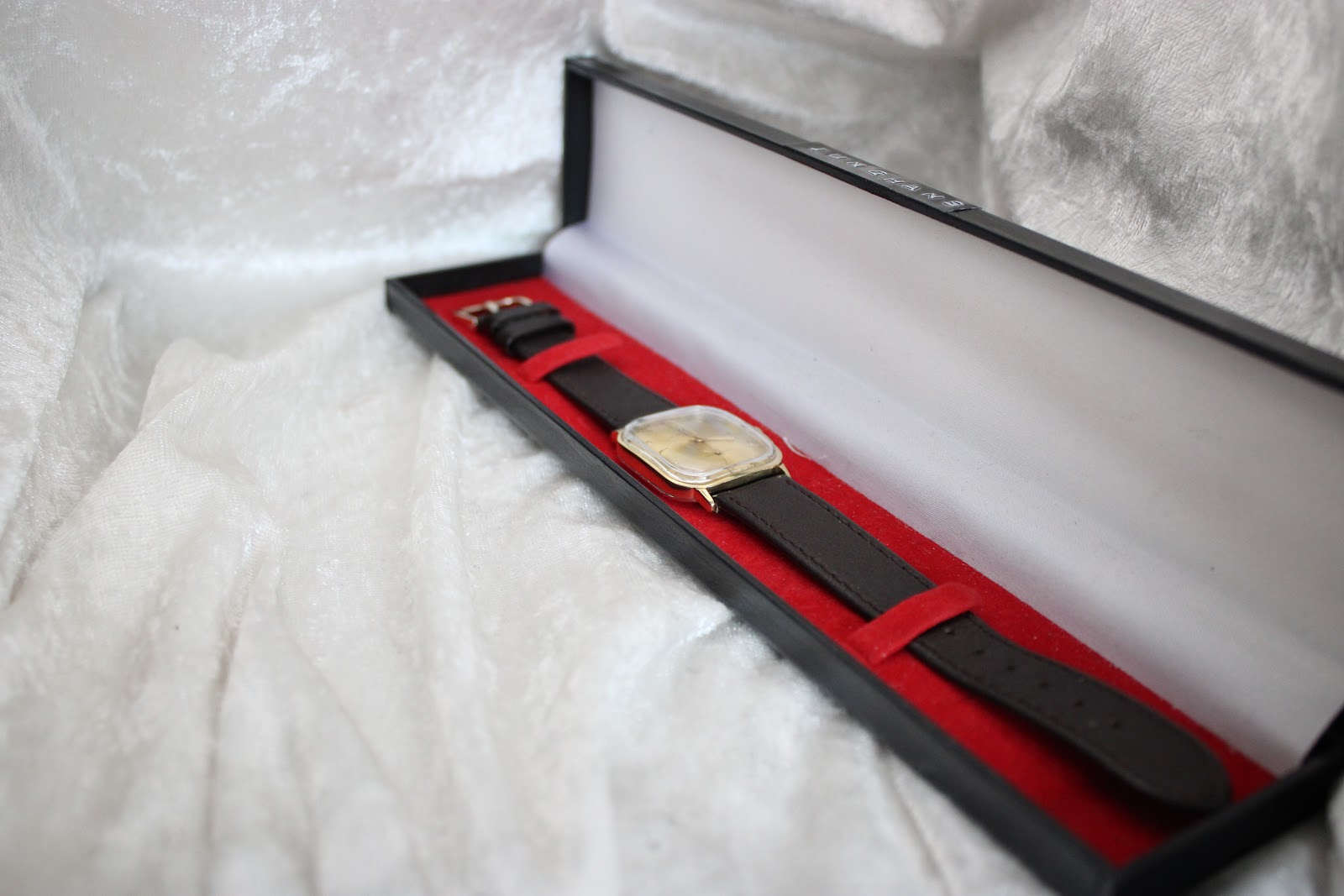 The Junghans watch resting in a black presentation box with a red velvet interior.