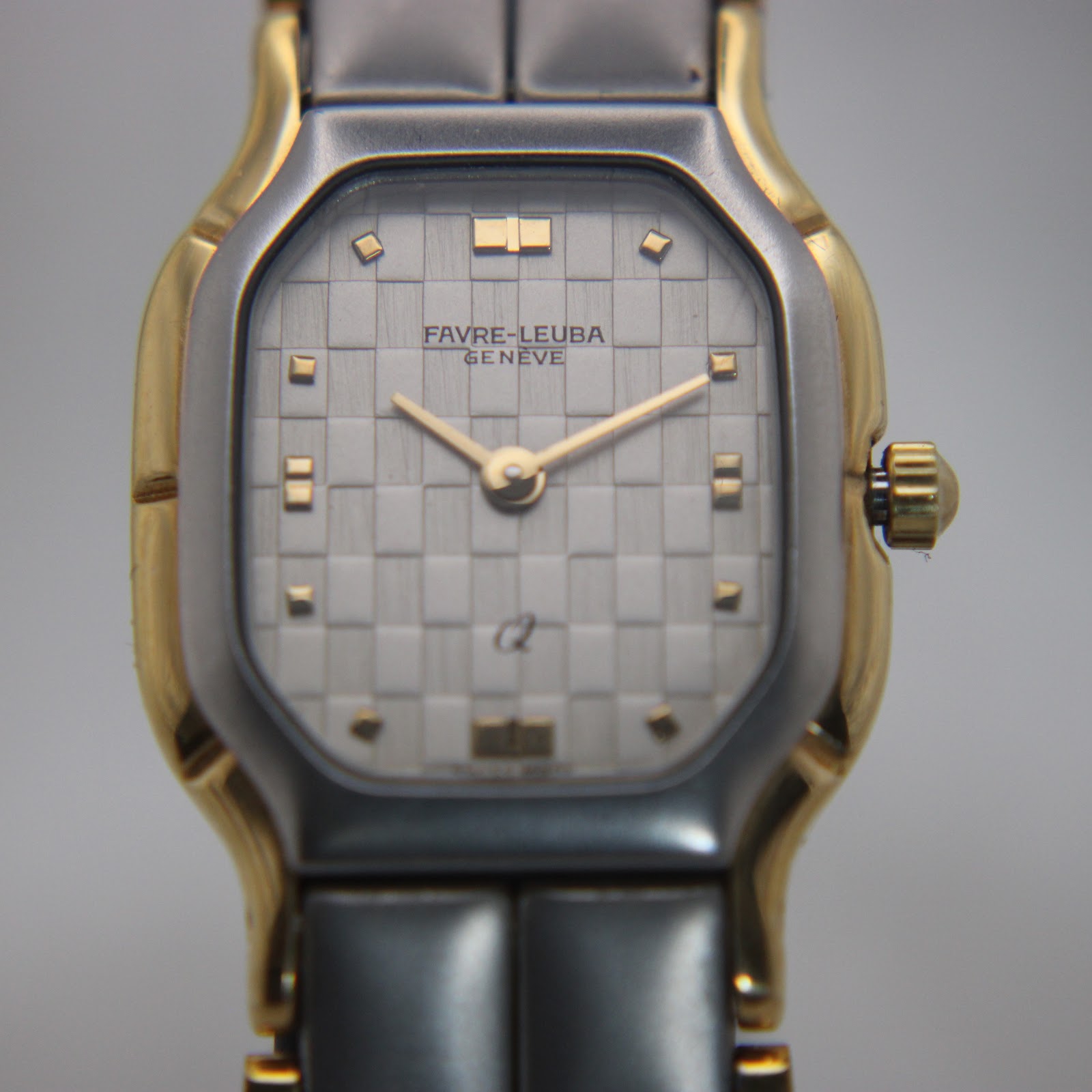 Close-up front view of the Favre-Leuba Genève watch dial, featuring a silver checkerboard pattern and gold-tone hands.