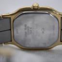 Close-up of the watch case back showing 'BASE METAL STAINLESS STEEL PACK', '3 ATM', 'QUARTZ', 'SWISS MADE', and reference numbers.