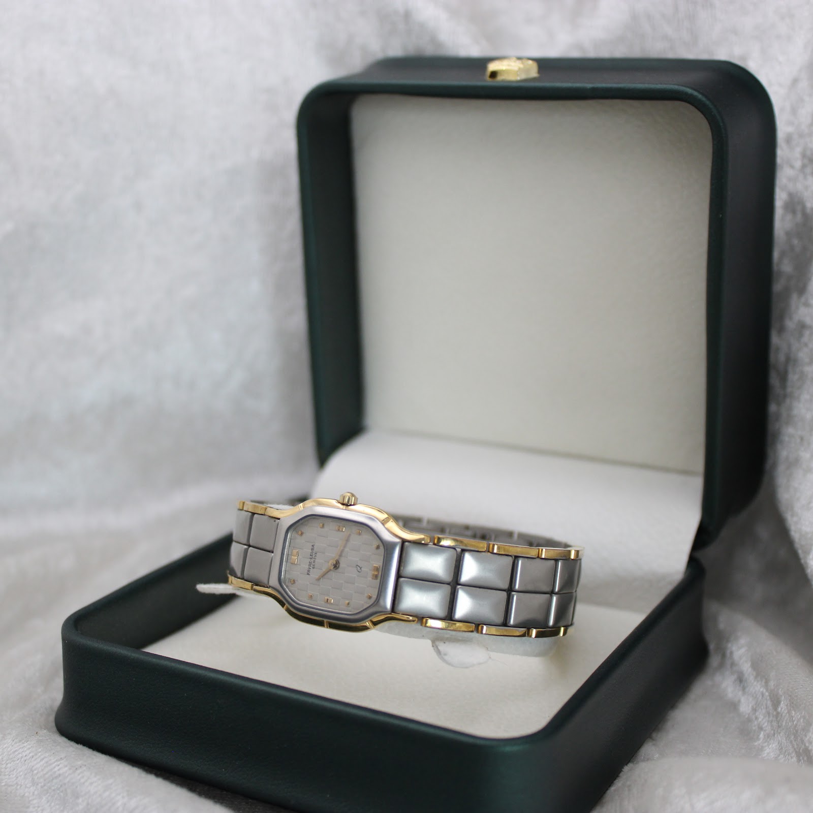 The Favre-Leuba watch resting inside an open dark green presentation box on a white background.