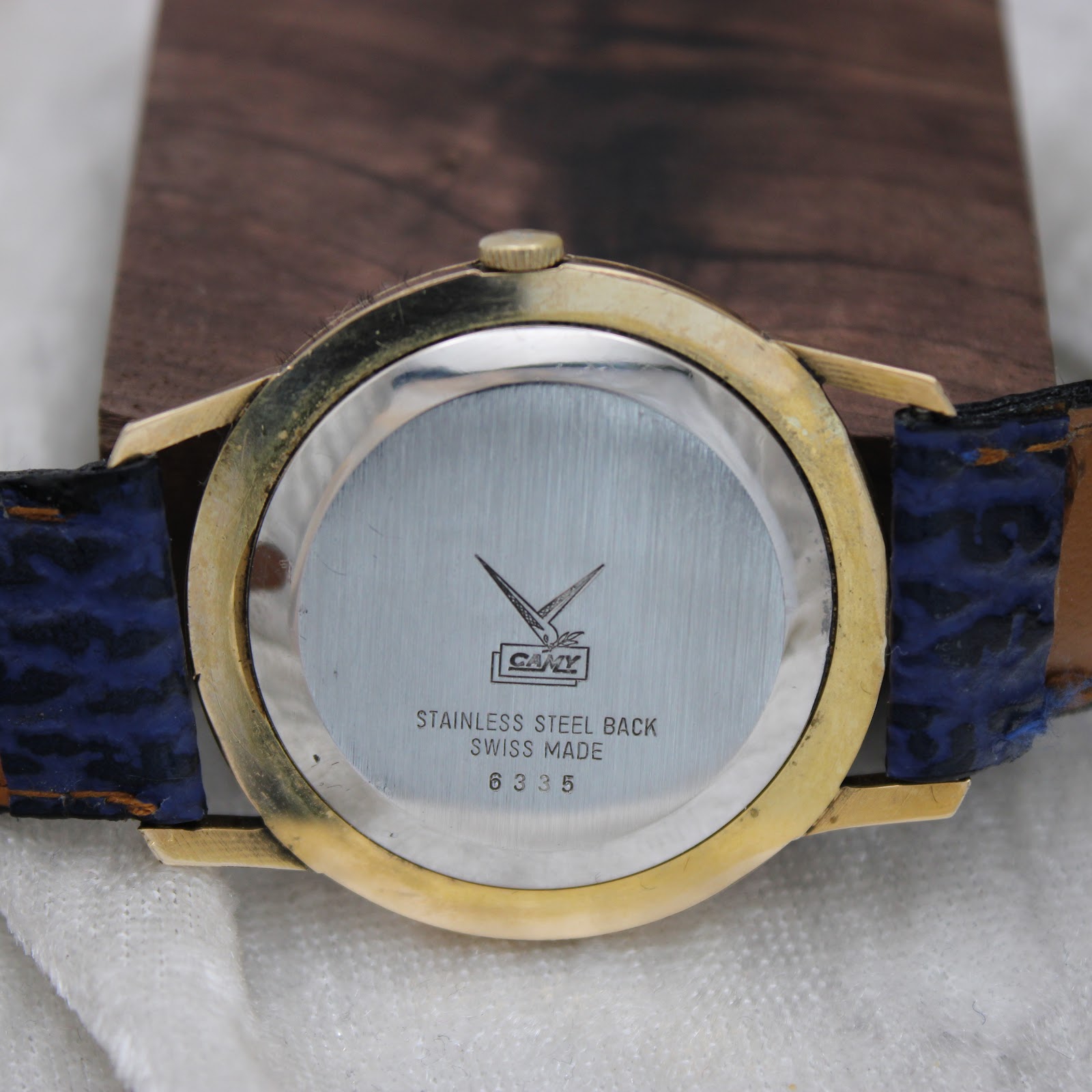 Close-up of the watch's stainless steel case back, engraved with the Camy logo, 'Stainless Steel Back', 'Swiss Made', and model number '6335'.