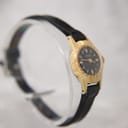 Angled side view of the Oris watch, highlighting its gold plated case and black leather strap on a clear display stand.