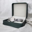 Tissot G330 watch with silver-tone case and bracelet, presented in an open dark green watch box.