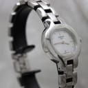 Angled close-up of the Tissot G330 watch on a black stand, highlighting the polished stainless steel case and bracelet.
