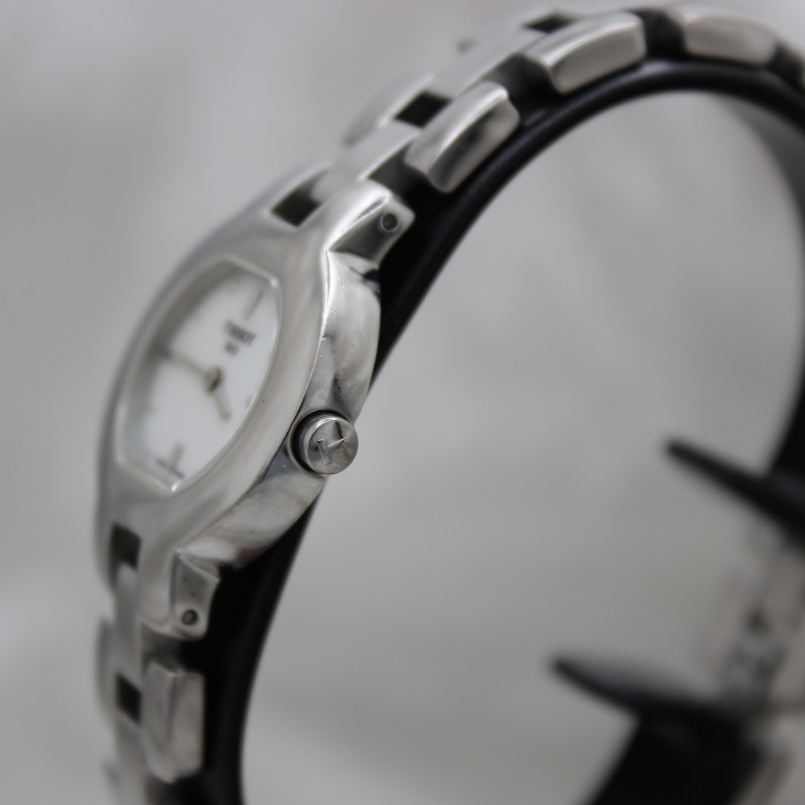 Close-up of the Tissot G330 watch crown, clearly showing the 'T' logo engraved on it.