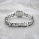 Rear view of the Tissot G330's integrated stainless steel bracelet, laid on a white textured surface.