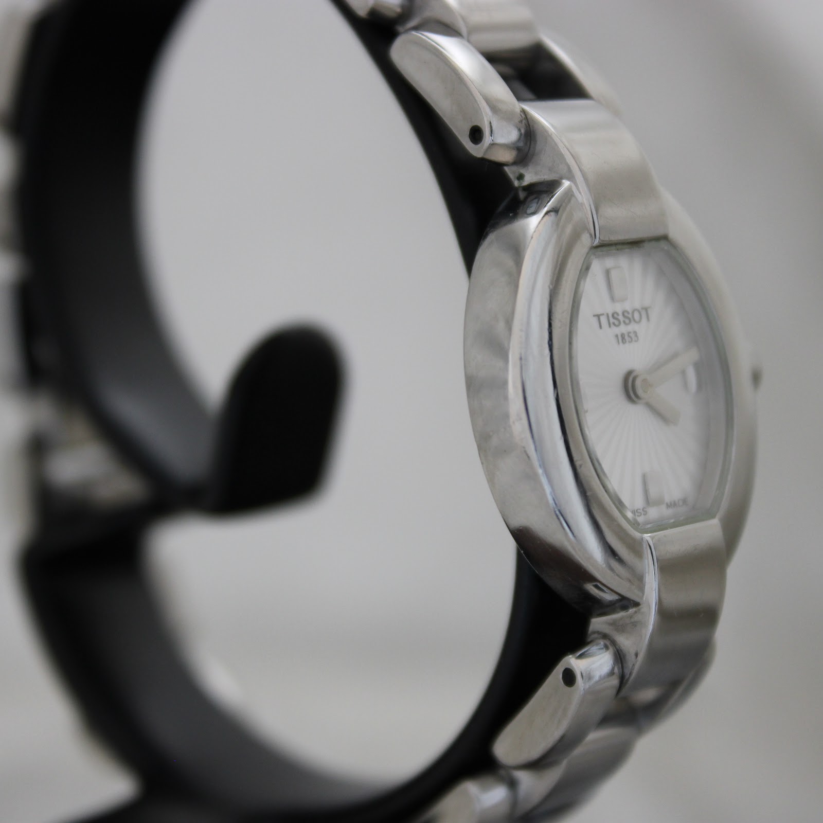 Angled side view of the Tissot G332 watch, highlighting the polished finish of the oval case and the integrated stainless steel bracelet.