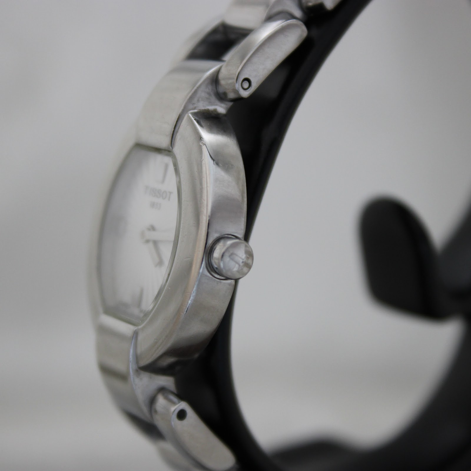 Close-up side profile of the Tissot G332 watch, showing the small crown and the seamless flow of the stainless steel bracelet.