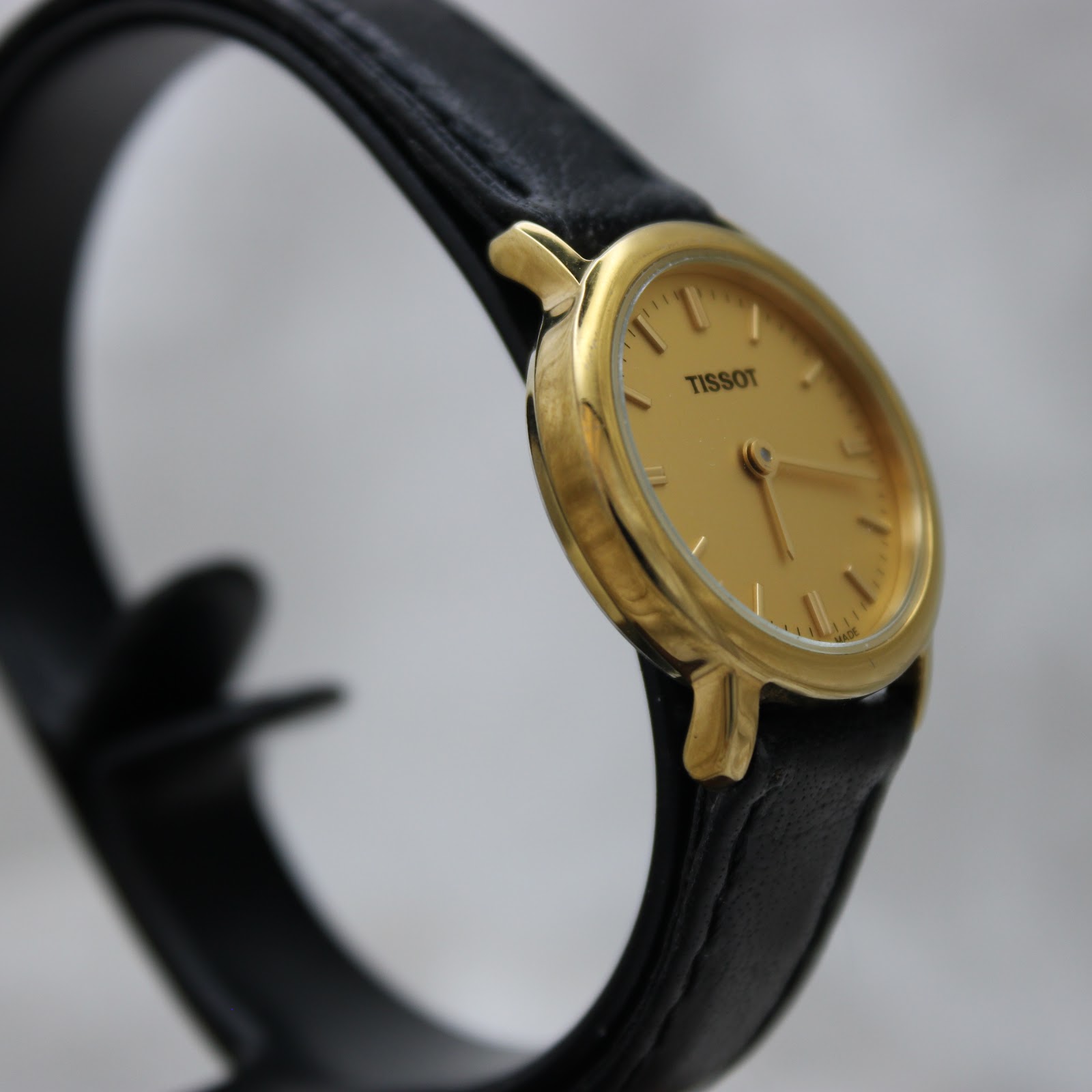 Close-up of the Tissot-signed buckle on the black leather strap.