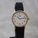 Front view of the Tissot T852K ladies' watch, showing the white guilloché dial with black Arabic numerals, gold-tone case, and black textured leather strap.