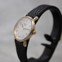 Angled view of the Tissot T852K watch from the right, highlighting the gold-tone case, crown, and the texture of the black leather strap.