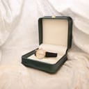 The Tissot T852K watch resting inside an open green presentation box, set against a soft white velvet surface.