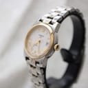 Angled view of the Tissot PR 50 watch showing the gold-tone bezel and crown on a watch stand.
