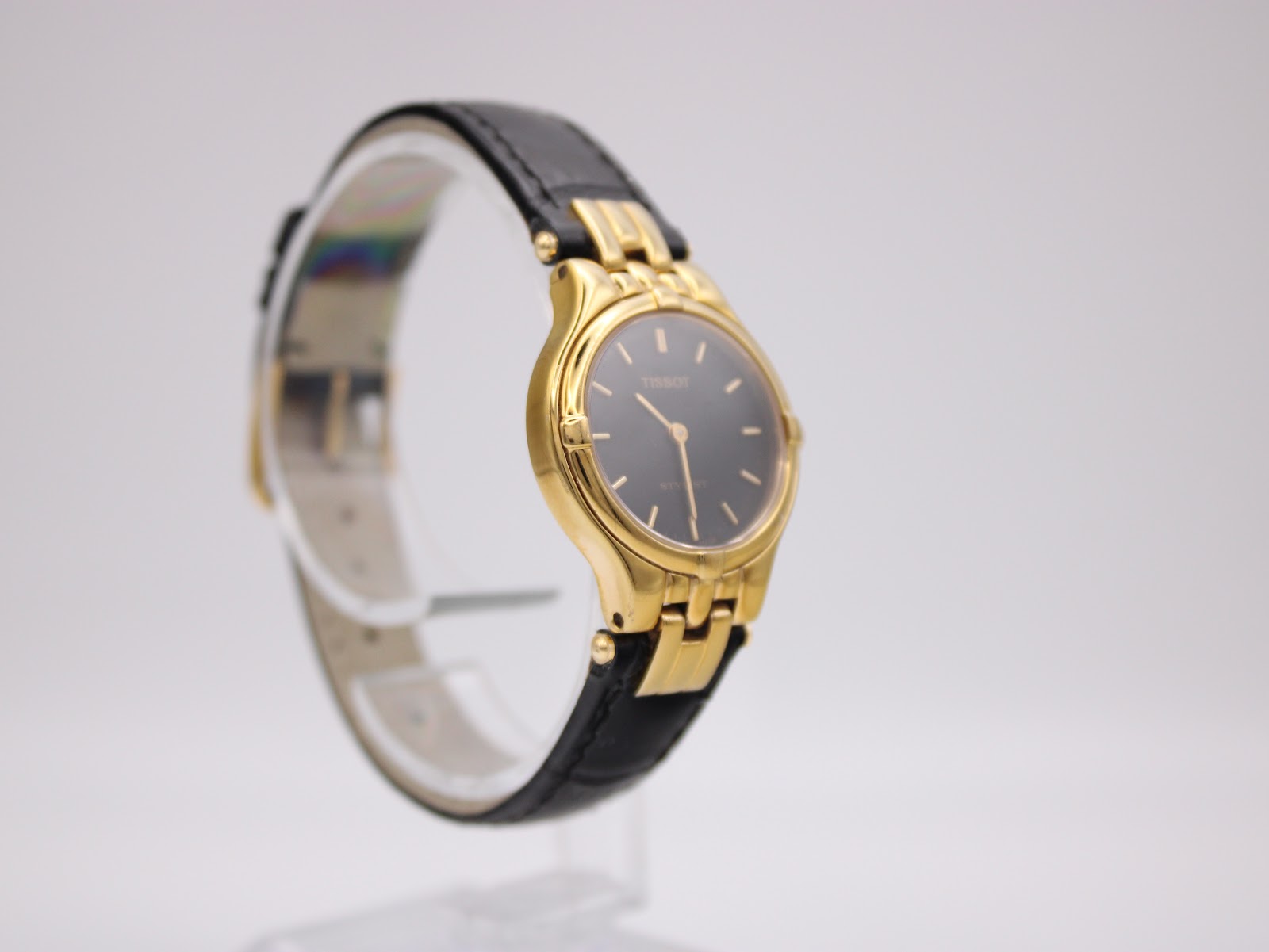 Close-up of Tissot Stylist black dial with gold-tone indices and hands.