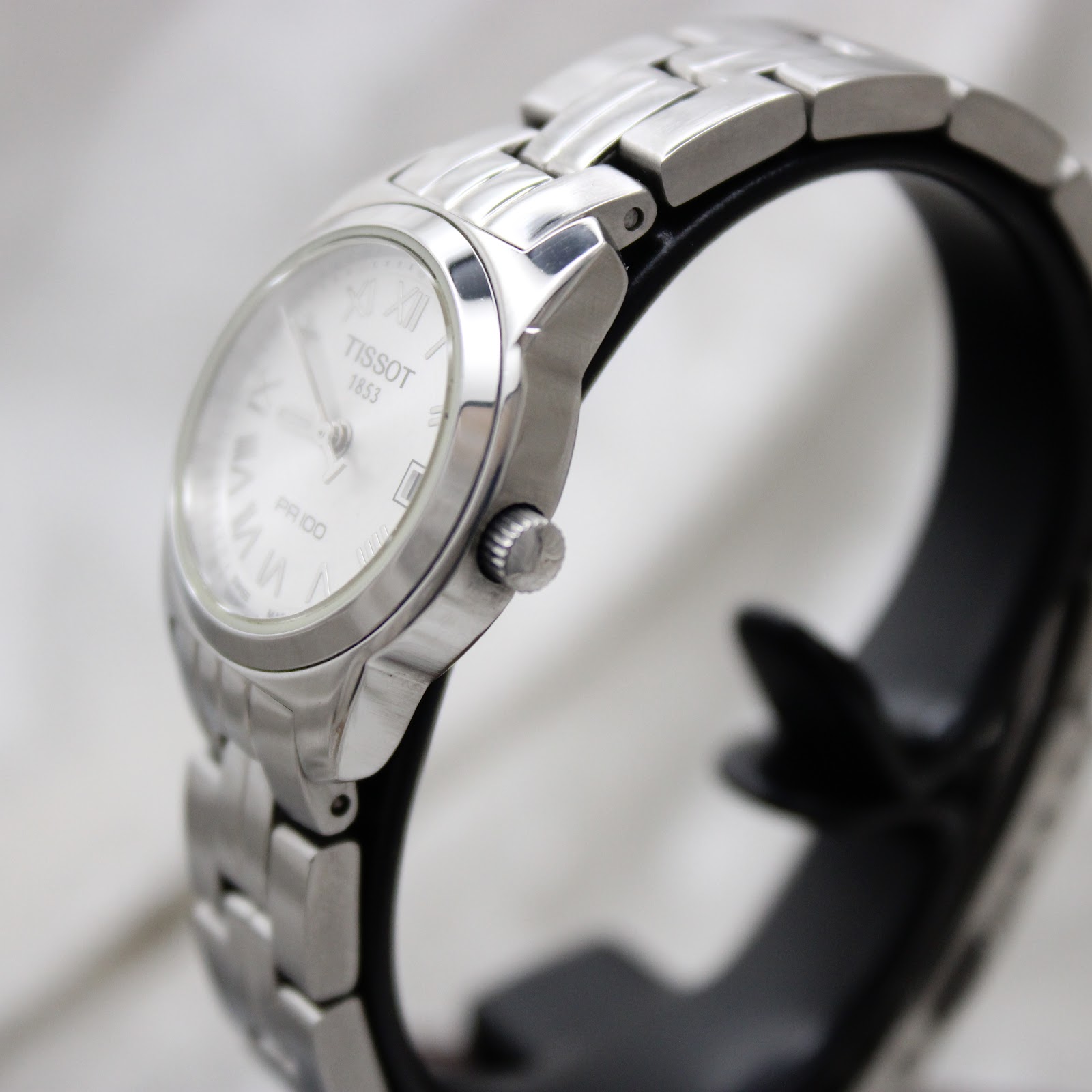 Side profile of Tissot PR 100 stainless steel case and integrated bracelet.